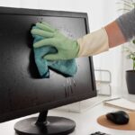 cleaning a computer monitor which is on the desk